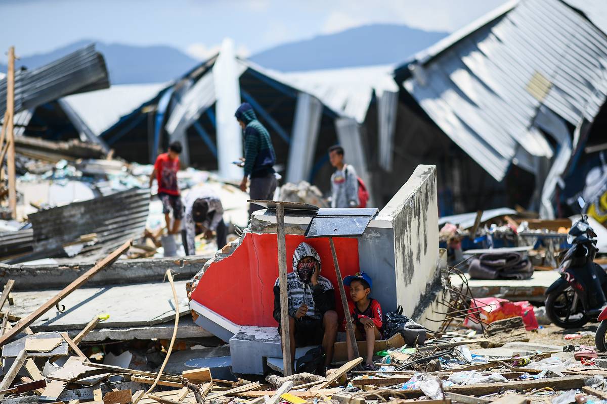 People sit, and forage amongst the ruins after an earthquake